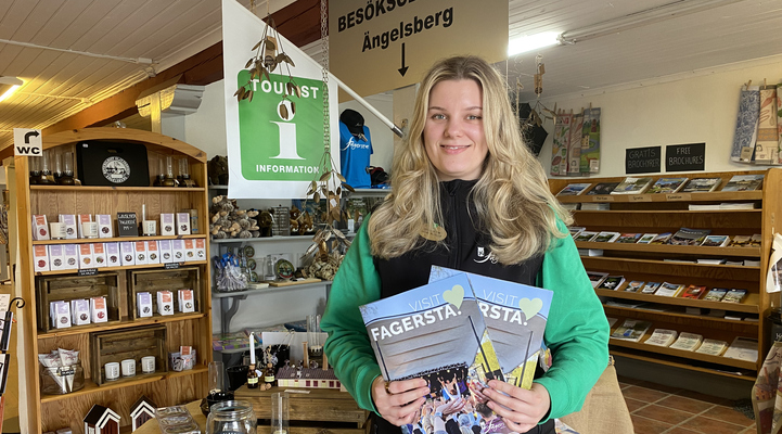 Eveline Wahlfeldt med turistbroschyrer i händerna på besökscentrum i Ängelsberg