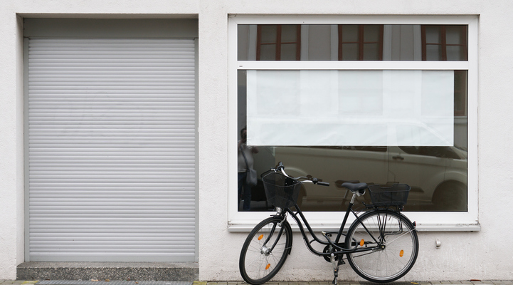 en cykel står utanför ett skyltfönster till en tillsynes tom butikslokal