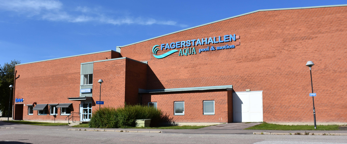 Fagerstahallens byggnad beklädd med tegel och en stor skylt med texten Fagerstahallen, Aqua, pool och motion.