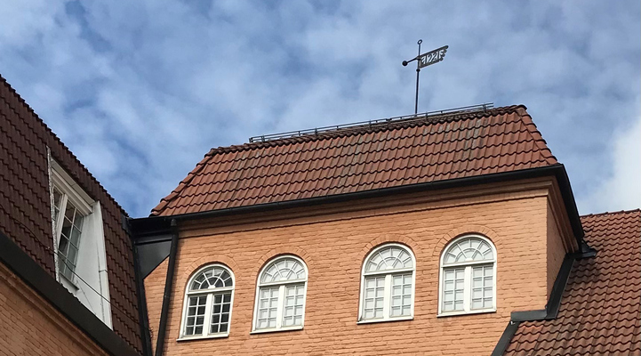 Risbroskolan, gul tegelbyggnad med en vindflöjel med årtalet 1921 på taket.