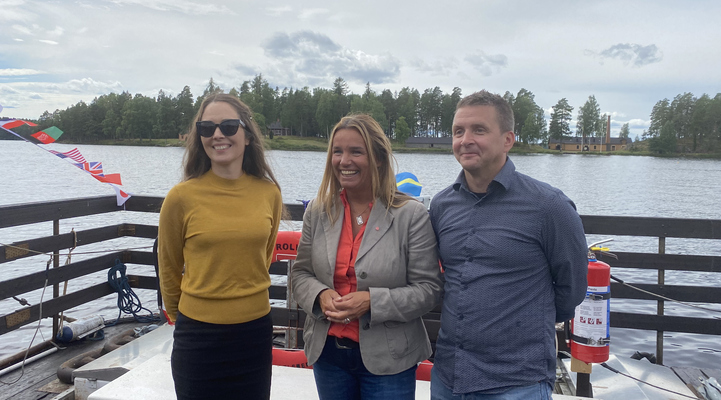  Kommunchef Karolina Berglund, landsbygdsministern och kommunalråd Marino Wallsten står på båtflotten som går ut till Oljeön. I bakgrunden syns Oljeön.