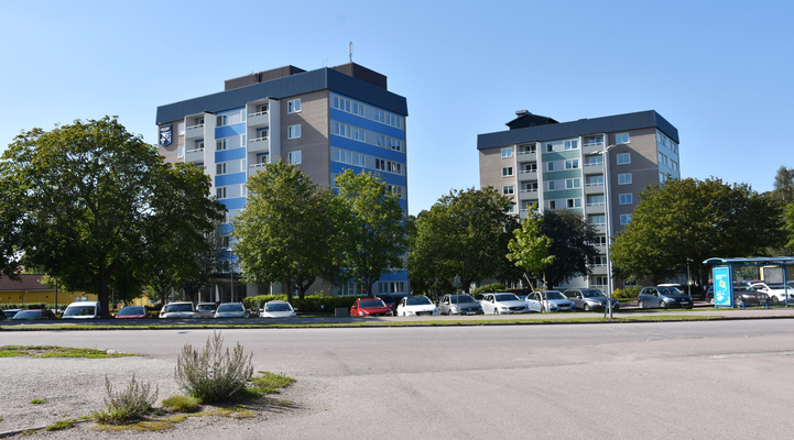 Fagerstas kommunhus. Två höga tegelbyggnader. Flera bilar står parkerade framför husen på parkeringen.