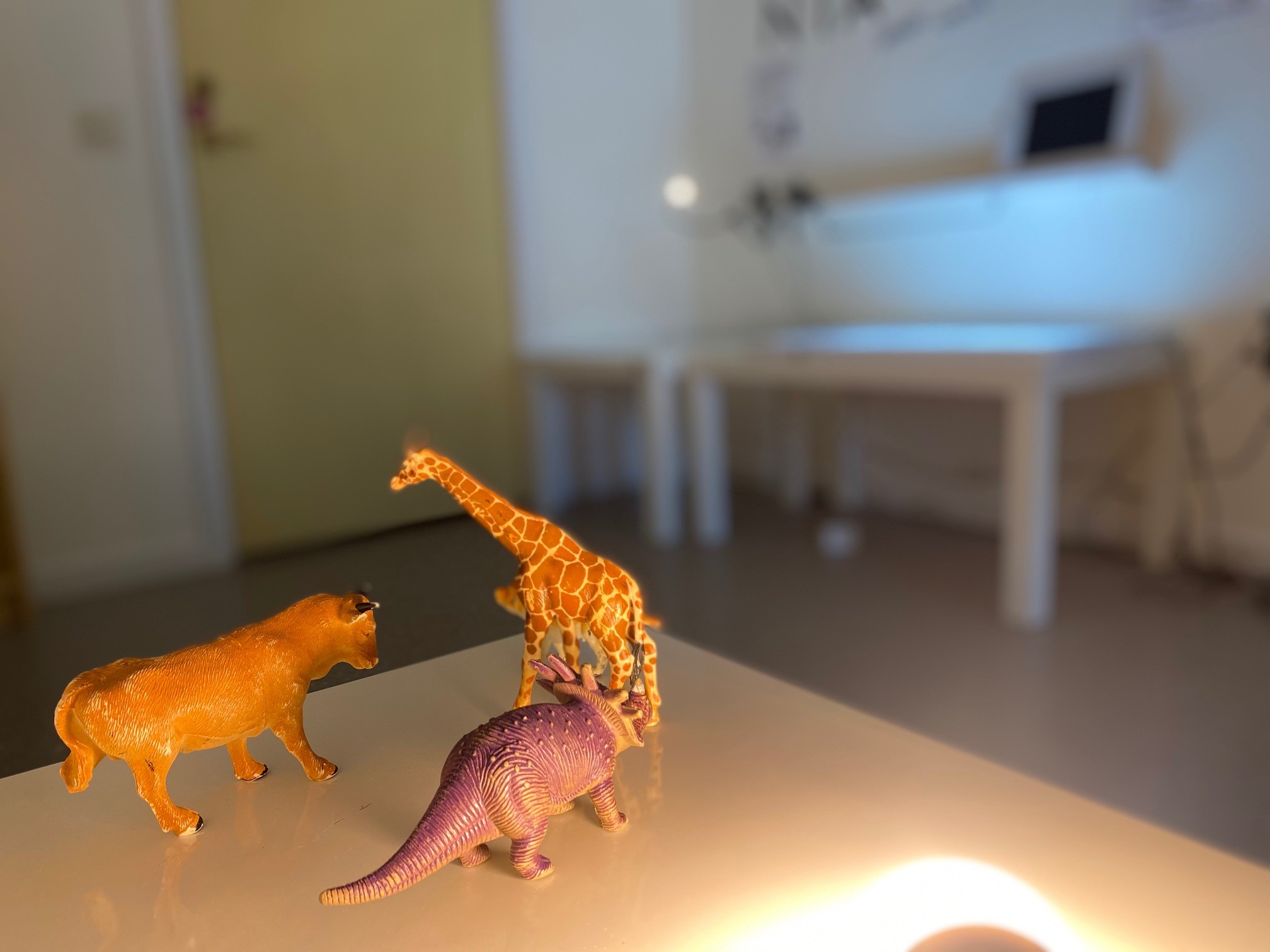 En bild på 3 dinosaurier som står uppställda på ett vitt bord