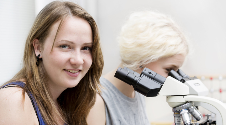 Två kvinnor sitter vid ett mikroskop