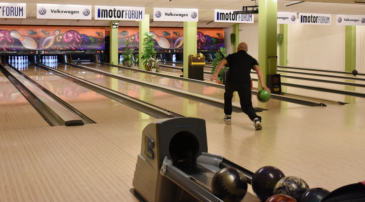 En man är på väg och ska kasta sitt bowlingklot på en bowlingbana där alla käglorna står uppradade längst ner.