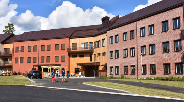 Några människor som står utanför en stor tegelbyggnad i olika färger.