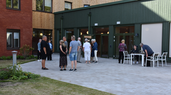 En grupp människor som står i utanför en tegelbygnad.