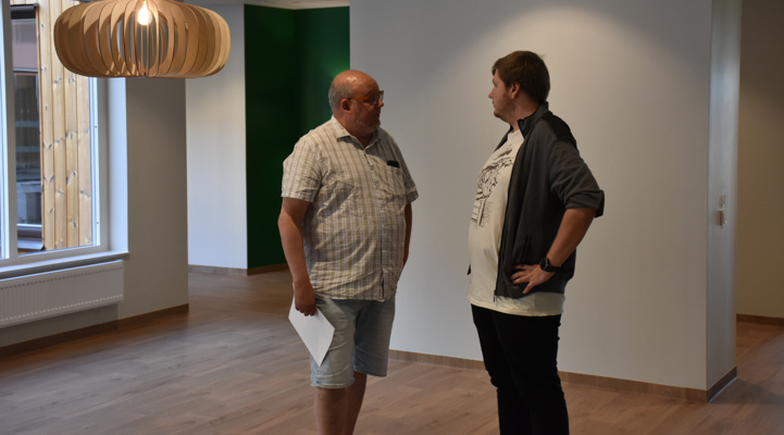 Två män som pratar med varandra i en lokal inomhus.