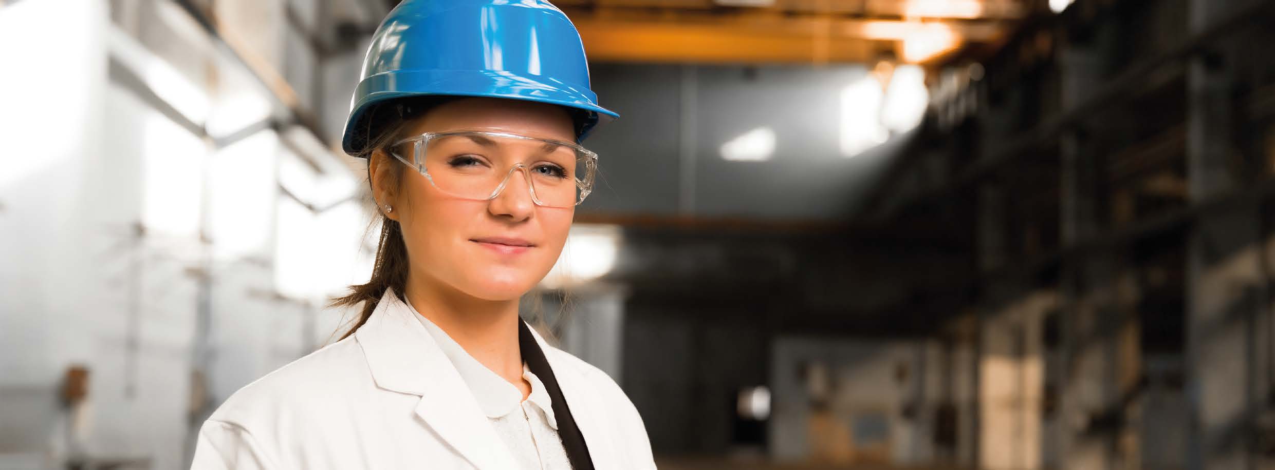 Kvinna med hjälm och skyddsglasögon i industrimiljö