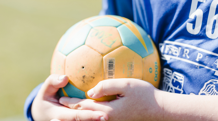 En ung person som håller en fotboll i sina händer.