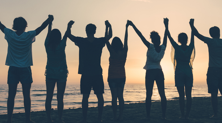 Group of People with Raised Arms looking at Sunset