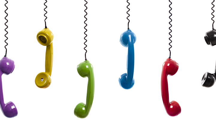 Flerfärgade telefoner upphängda i telefonsladden, isolerad på vit bakgrund