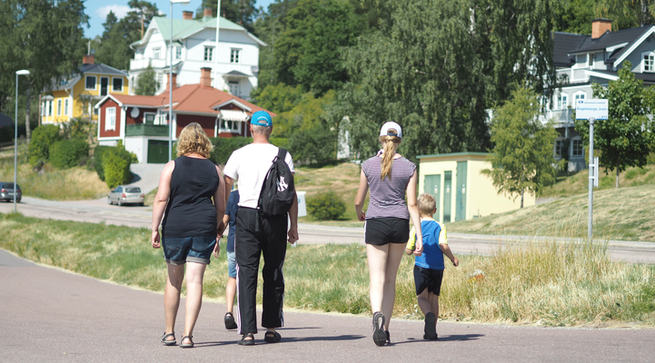 En familj med två vuxna och tre barn promenerar från Ängelsbergs stationshus