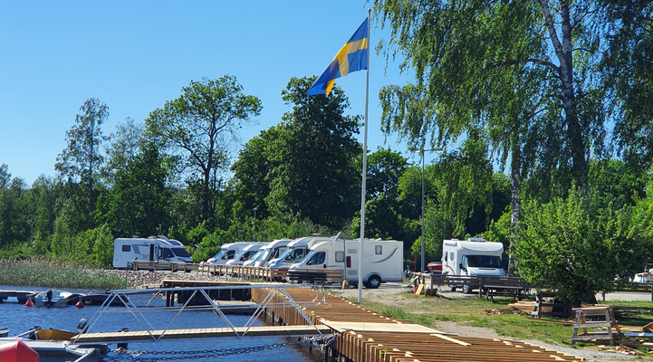 Västanfors båthamn. Svenska flaggan. Husbilar i bakgrunden